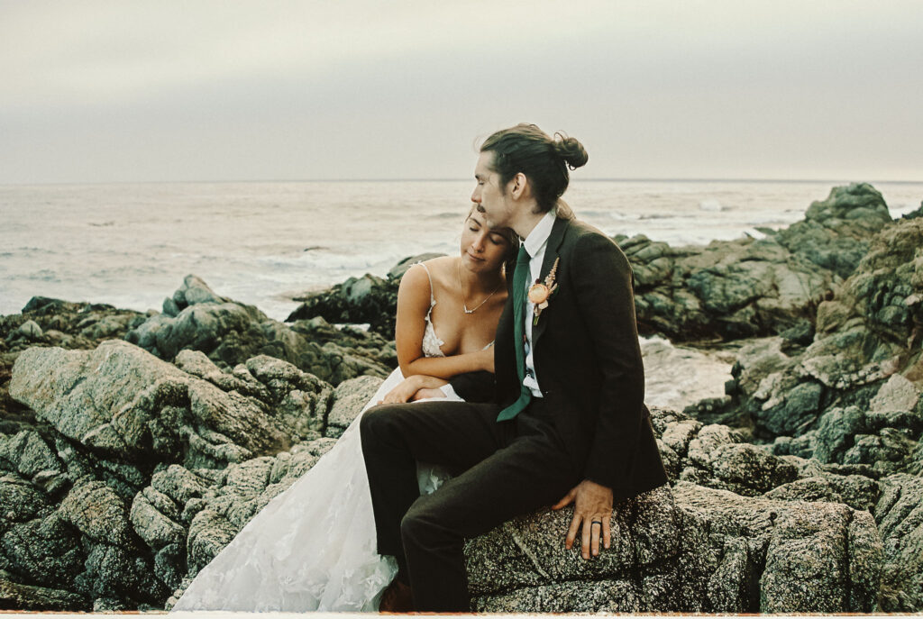 A couple relaxing on the beach during their Big Sur elopement, making the most out of their wedding day.